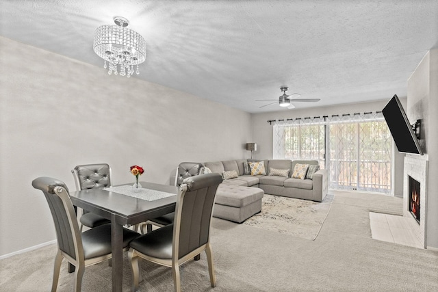 dining room featuring a textured ceiling, light colored carpet, and ceiling fan with notable chandelier