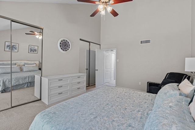 bedroom with ceiling fan, multiple closets, high vaulted ceiling, and light colored carpet