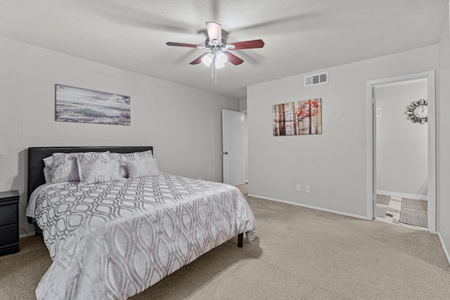 bedroom with a textured ceiling, light colored carpet, and ceiling fan