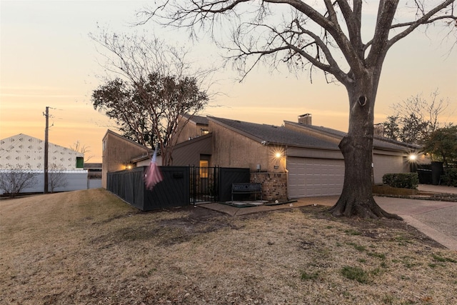 property exterior at dusk featuring a yard and a garage