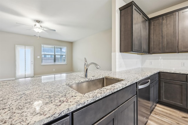 kitchen with light stone counters, sink, dark brown cabinets, and dishwasher