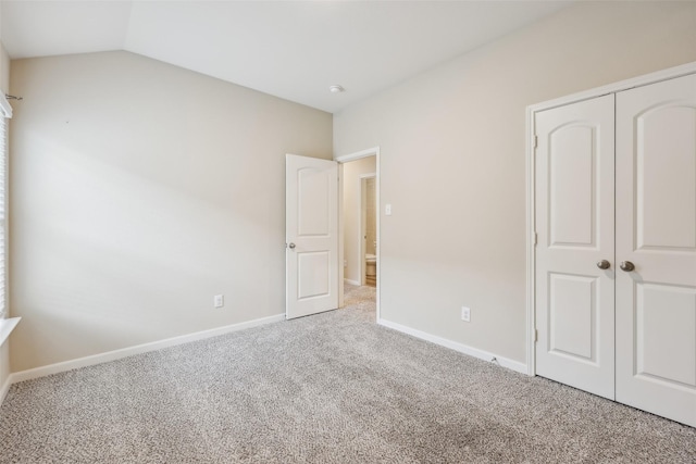 unfurnished bedroom with a closet, vaulted ceiling, and carpet