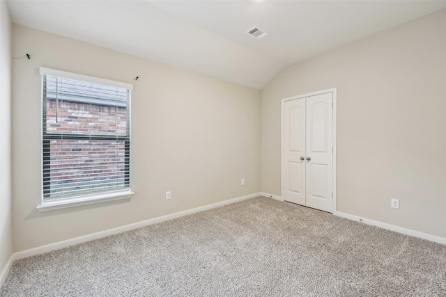 unfurnished bedroom with lofted ceiling, a closet, and carpet flooring