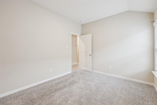 carpeted spare room featuring vaulted ceiling