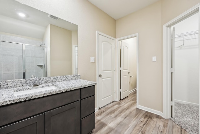 bathroom with vanity, a shower with shower door, and wood-type flooring