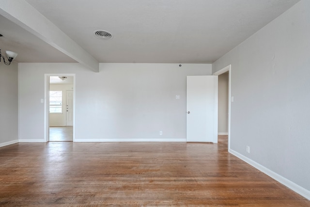 empty room featuring hardwood / wood-style floors and beam ceiling