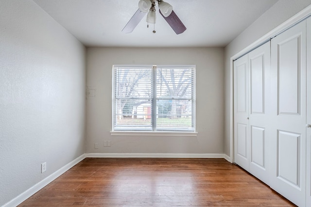 unfurnished bedroom with ceiling fan, wood-type flooring, and a closet