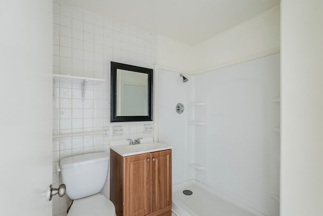 bathroom with a shower, tile walls, vanity, and toilet