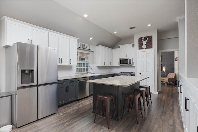 kitchen featuring white cabinetry, stainless steel appliances, a kitchen breakfast bar, and a kitchen island