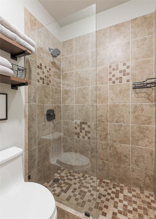 bathroom with a tile shower and toilet