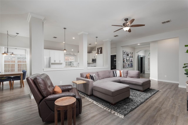 living room featuring a healthy amount of sunlight, ceiling fan, wood-type flooring, and decorative columns