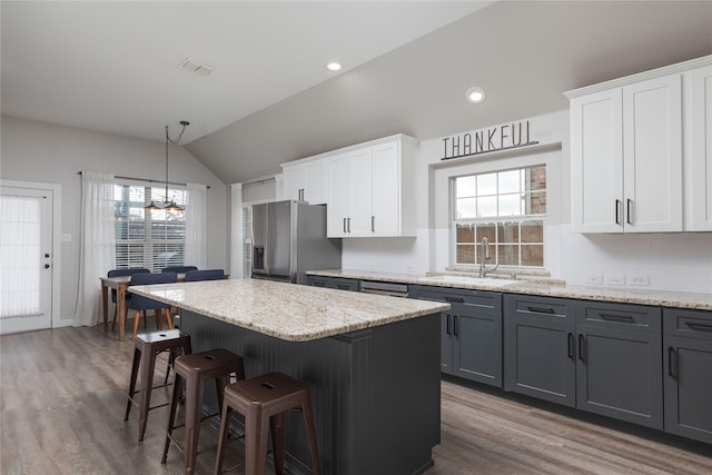 kitchen featuring stainless steel fridge, a center island, sink, and white cabinets