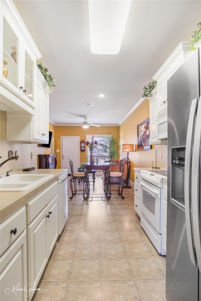 kitchen with white appliances, ornamental molding, sink, and white cabinets