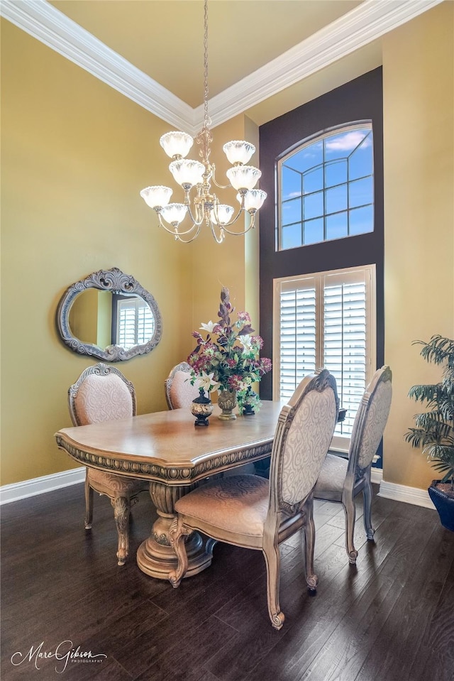 dining space featuring a notable chandelier, wood-type flooring, ornamental molding, and a high ceiling