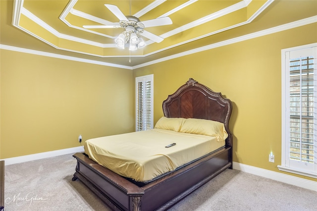 bedroom with ceiling fan, light colored carpet, ornamental molding, and a tray ceiling