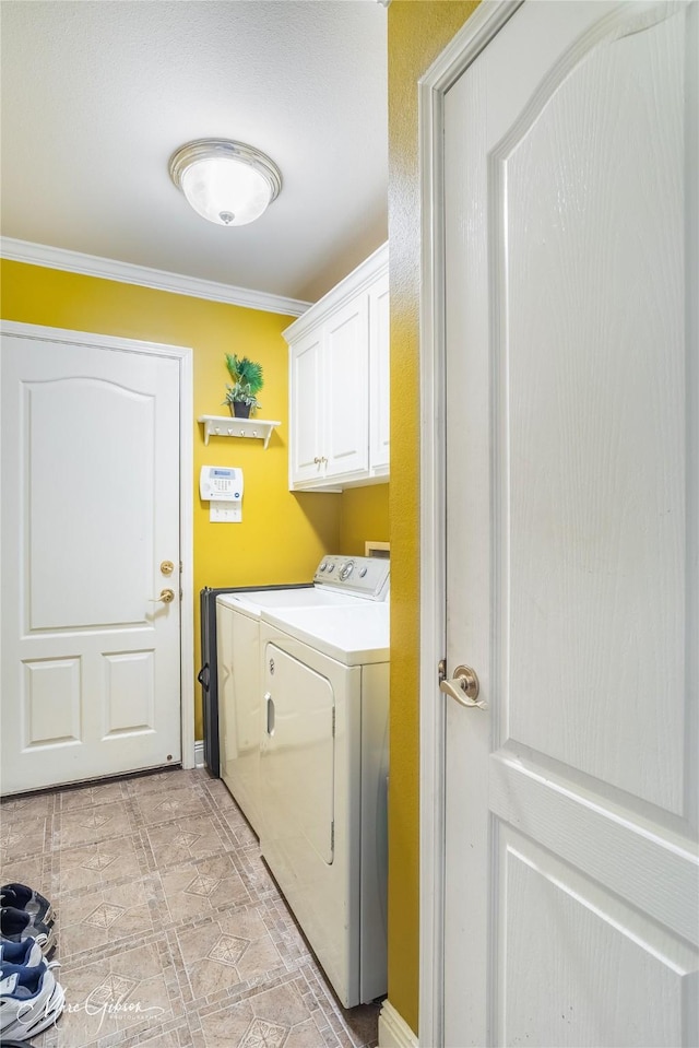 clothes washing area featuring ornamental molding, cabinets, and washing machine and clothes dryer