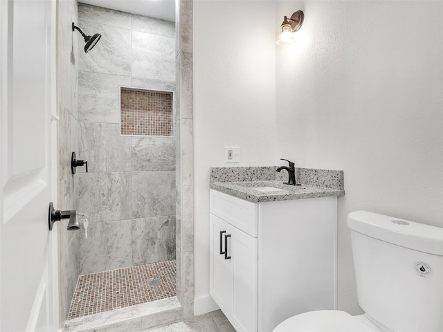 bathroom with vanity, a tile shower, and toilet