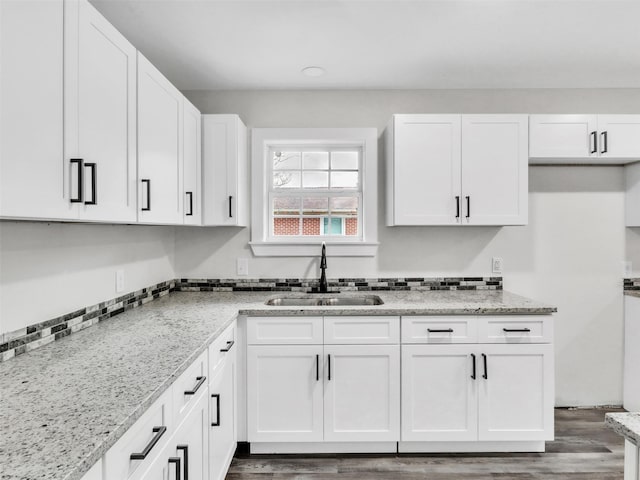 kitchen featuring dark hardwood / wood-style floors, white cabinetry, sink, and light stone counters