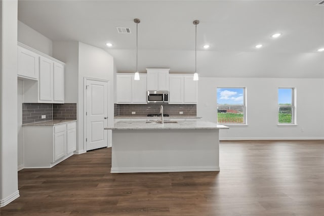 16109 Garden Dr, Celina, TX 75009 - kitchen with dark wood-type flooring, white cabinetry, visible vents, a kitchen island with sink, and stainless steel microwave