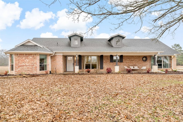 view of front of house featuring brick siding and a shingled roof