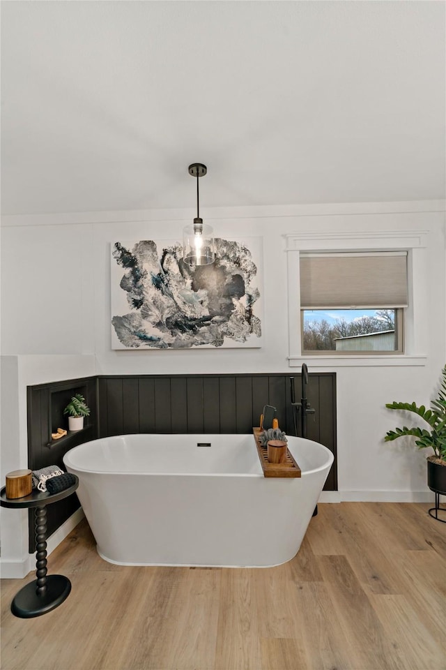 bathroom featuring wood finished floors and a freestanding bath