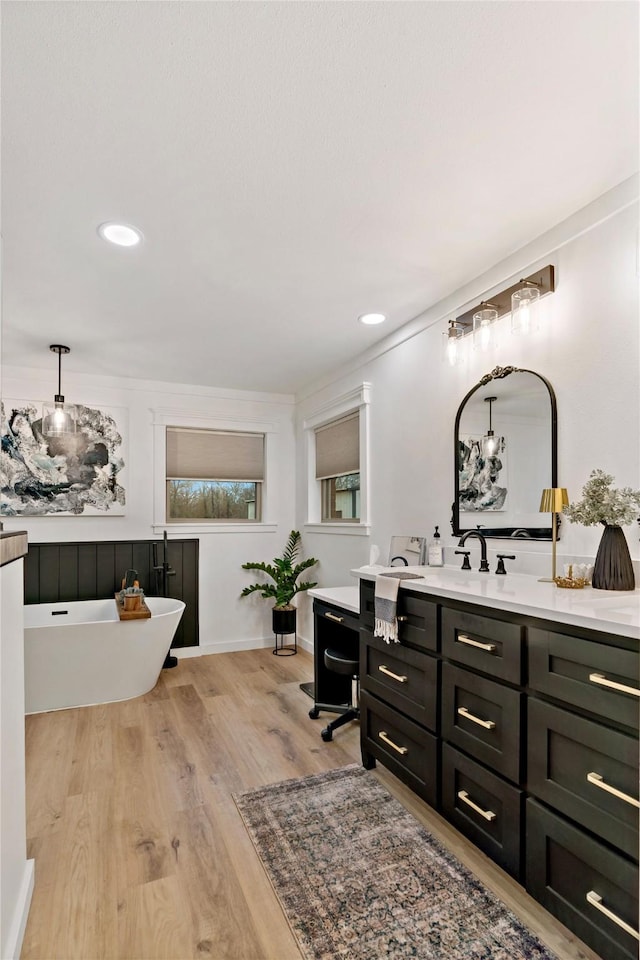 bathroom with wood-type flooring, vanity, crown molding, and a tub to relax in