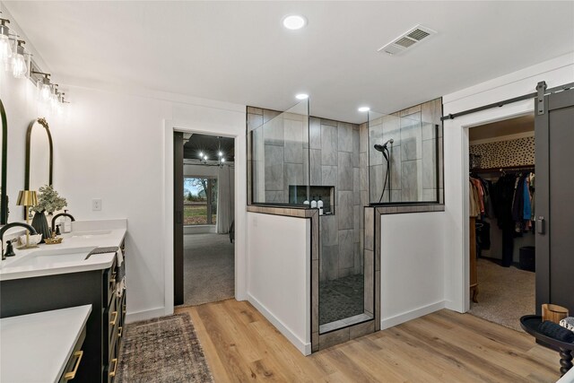 bathroom featuring visible vents, a walk in shower, double vanity, wood finished floors, and a sink