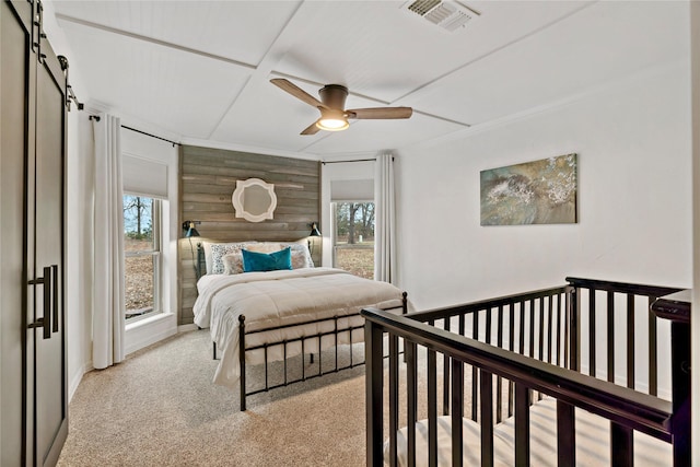 bedroom featuring visible vents, ceiling fan, wood walls, light carpet, and a barn door