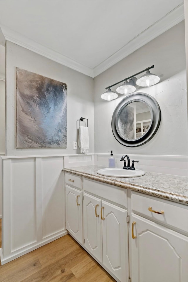 bathroom with hardwood / wood-style flooring, ornamental molding, and vanity