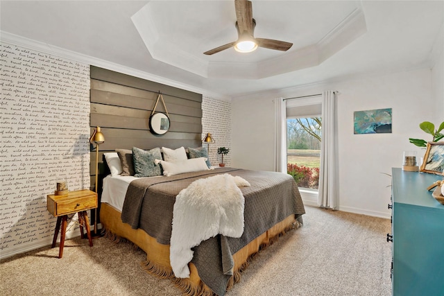 carpeted bedroom with a tray ceiling, crown molding, baseboards, and ceiling fan