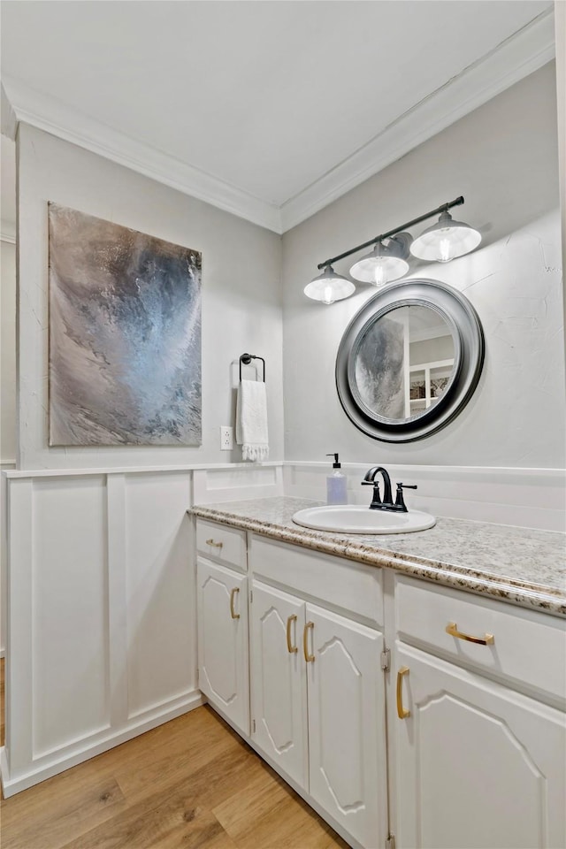 bathroom featuring wood finished floors, crown molding, and vanity