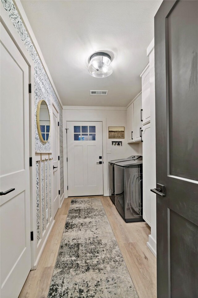 clothes washing area featuring visible vents, light wood-style flooring, washer and dryer, cabinet space, and crown molding