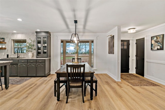 dining room featuring recessed lighting, baseboards, crown molding, and light wood-style flooring
