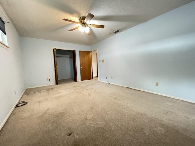 unfurnished bedroom featuring a textured ceiling, light colored carpet, visible vents, baseboards, and a closet