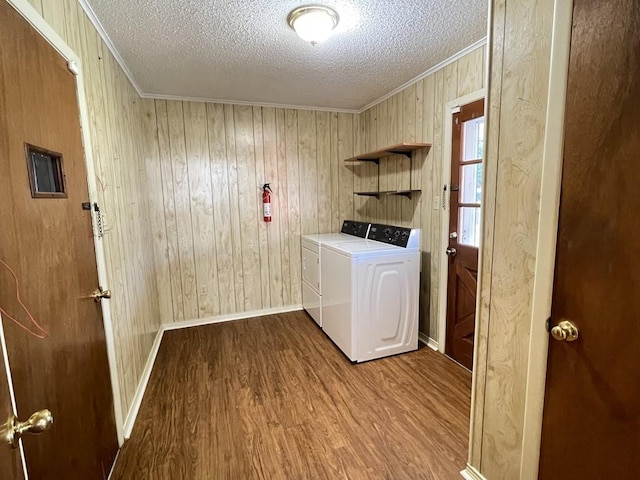 laundry area with laundry area, washer and clothes dryer, ornamental molding, wood finished floors, and a textured ceiling