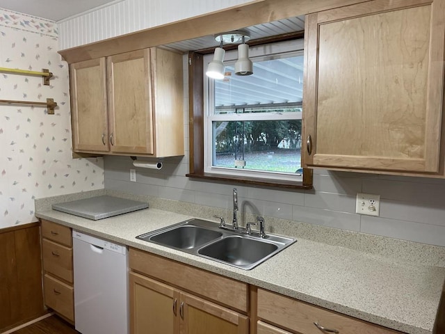 kitchen with light countertops, white dishwasher, a sink, and wallpapered walls