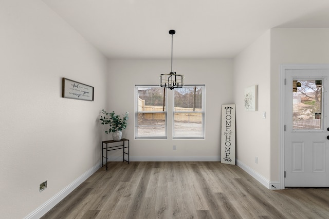 unfurnished dining area with an inviting chandelier and light wood-type flooring