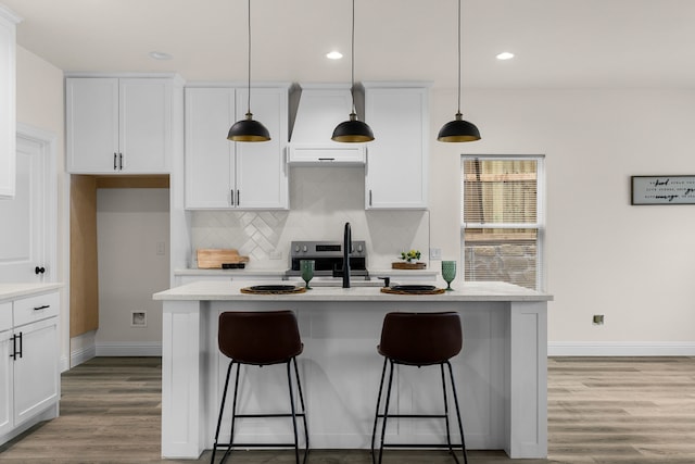 kitchen featuring white cabinetry, an island with sink, pendant lighting, and backsplash