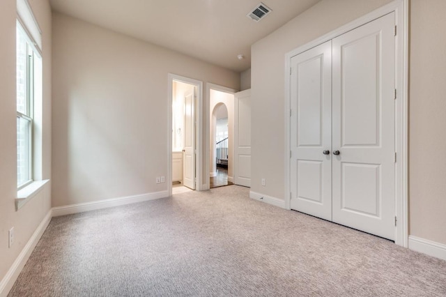 unfurnished bedroom featuring a closet, connected bathroom, and light carpet