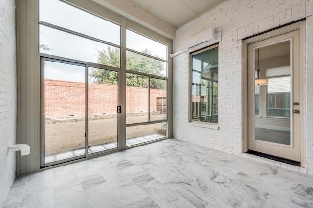 unfurnished sunroom featuring plenty of natural light and an AC wall unit