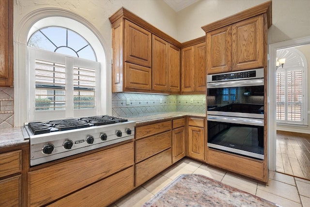 kitchen featuring backsplash, stainless steel appliances, light tile patterned floors, and a wealth of natural light