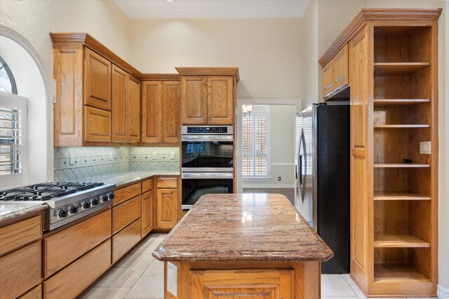 1604 Bridle Path, Corsicana, TX 75110 - kitchen with appliances with stainless steel finishes, backsplash, brown cabinets, and light tile patterned floors