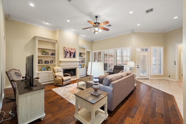 living room featuring hardwood / wood-style flooring, crown molding, ceiling fan, and built in shelves