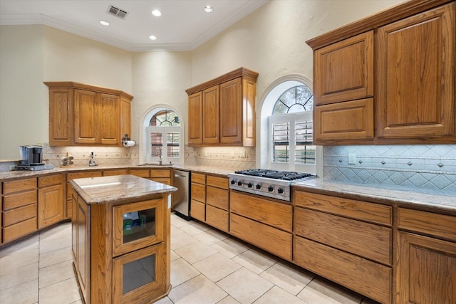 kitchen featuring appliances with stainless steel finishes, a center island, light tile patterned floors, crown molding, and light stone countertops