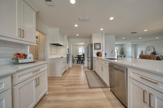 kitchen featuring sink, tasteful backsplash, light hardwood / wood-style flooring, appliances with stainless steel finishes, and white cabinets