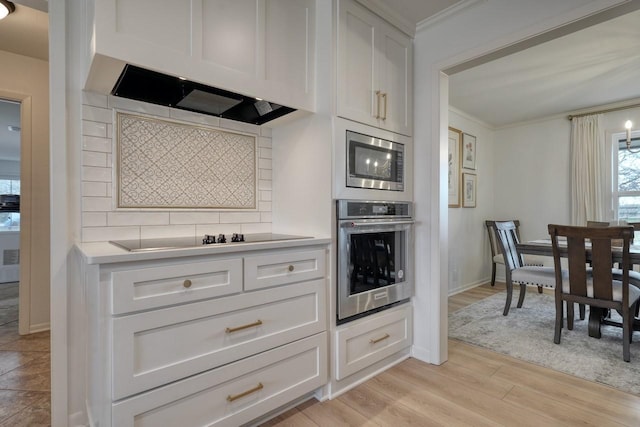 kitchen featuring backsplash, ornamental molding, appliances with stainless steel finishes, and white cabinets