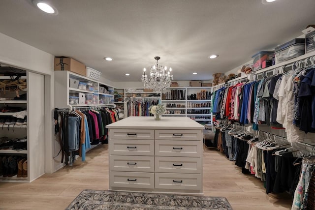 walk in closet with light hardwood / wood-style floors and a notable chandelier