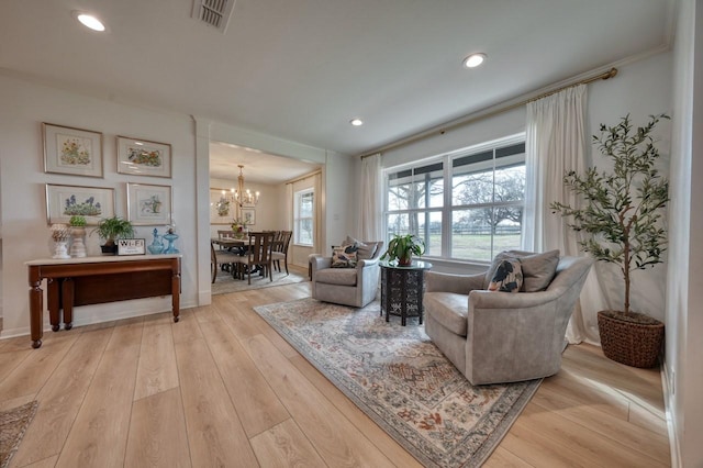 living room with an inviting chandelier and light wood-type flooring