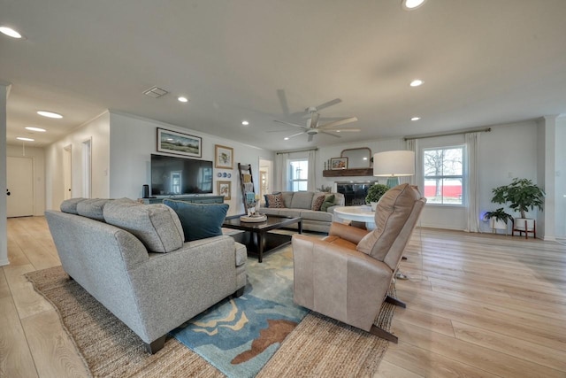 living room with ceiling fan, ornamental molding, and light hardwood / wood-style floors