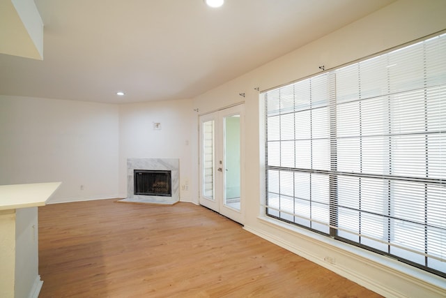 unfurnished living room with french doors, a fireplace, and light wood-type flooring